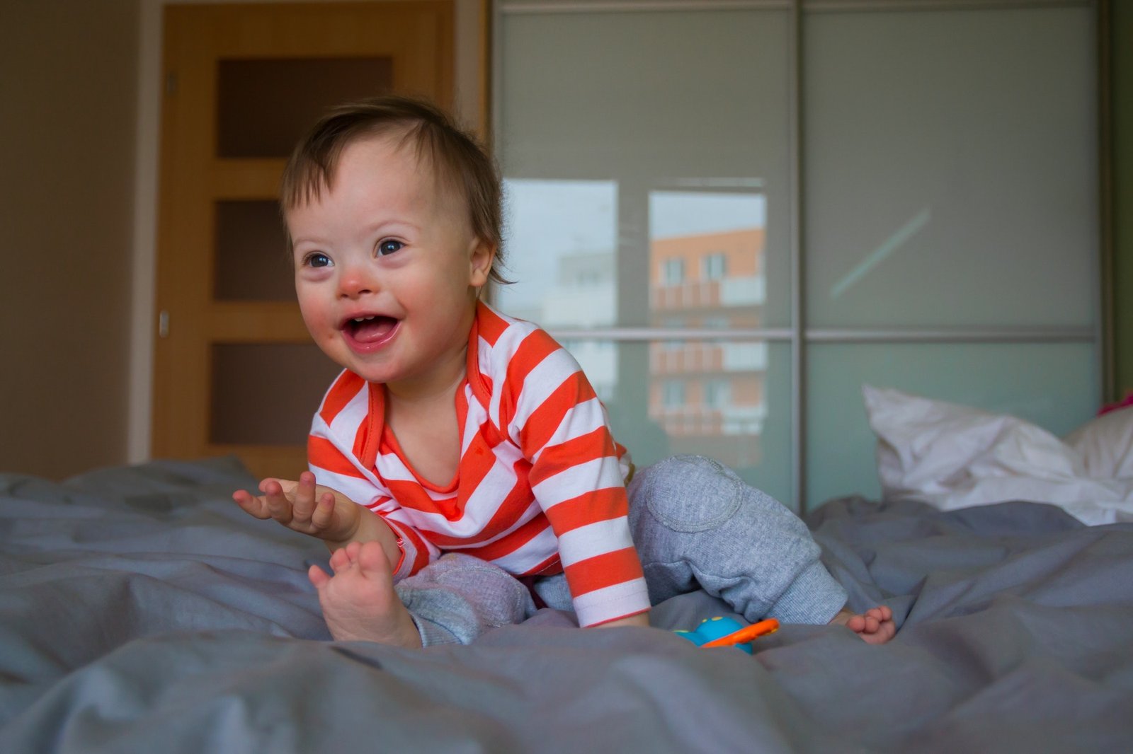 Cute baby boy with Down syndrome in the bed|