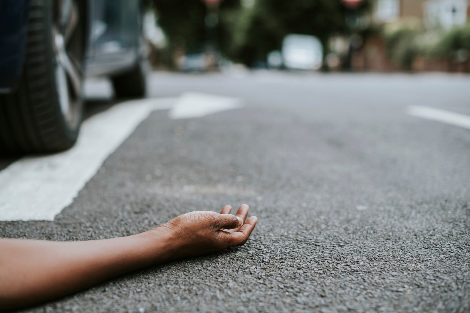Person lying on the ground after a car accident|